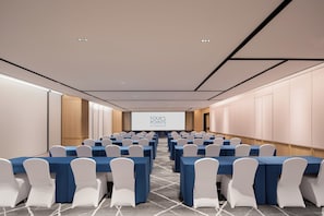 A conference room with rows of tables and chairs, a projection screen, and a carpeted floor. - Four Points By Sheraton Guangzhou Huangpu (Guangzhou)