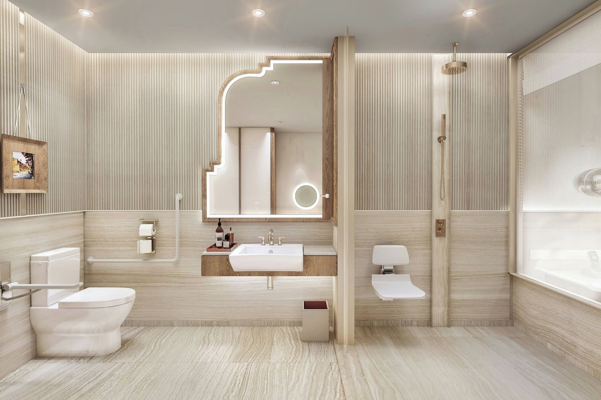 A modern bathroom with a large mirror, a bathtub, a toilet, and a sink.