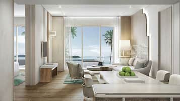 A modern hotel room with a wooden floor, a dining area with a table and chairs, a sofa, a TV, and a view of the sea.
