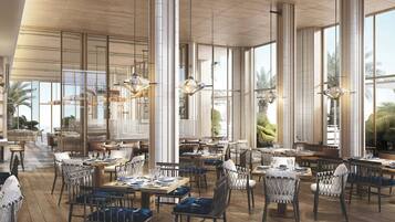 A spacious restaurant with high ceilings, large windows, and modern furnishings.