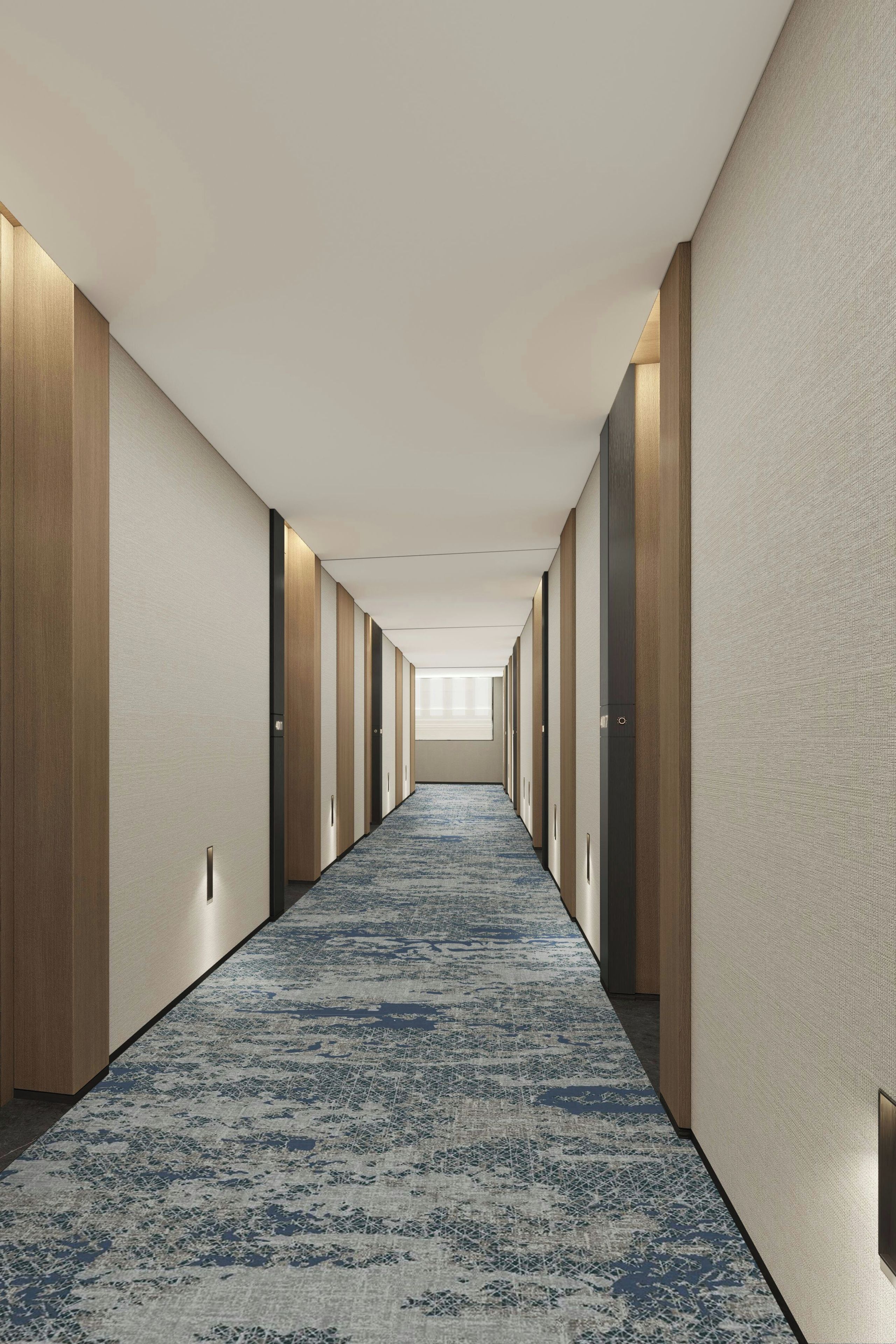 A hotel hallway with a blue patterned carpet, wooden paneling on the walls, and a series of doors leading to rooms.