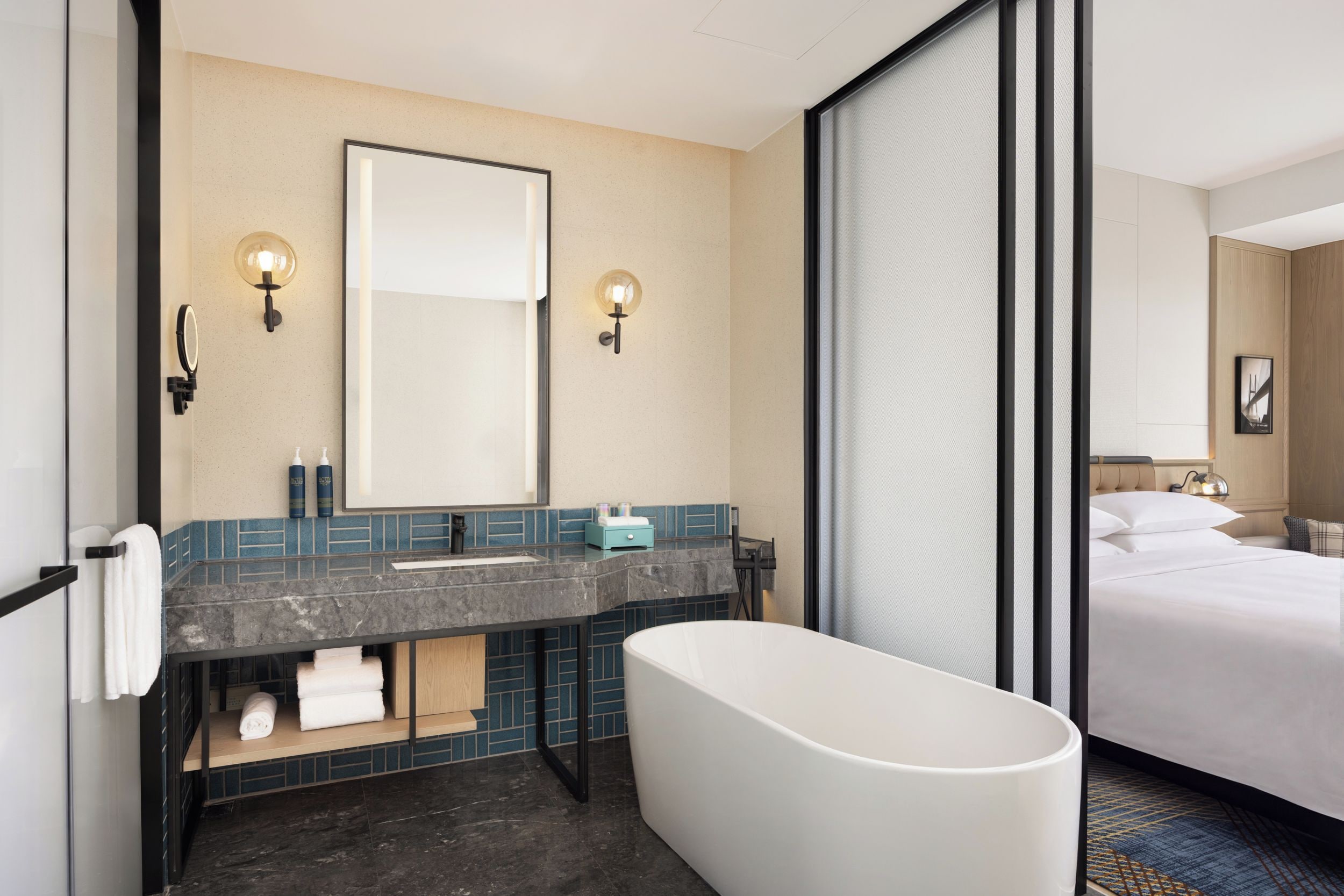 A modern bathroom with a bathtub, a large mirror, and a vanity with a sink.