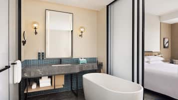 A modern bathroom with a bathtub, a large mirror, and a vanity with a sink.