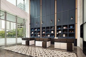 A modern interior with a large window, a patterned floor, and a wall with shelves displaying various items.