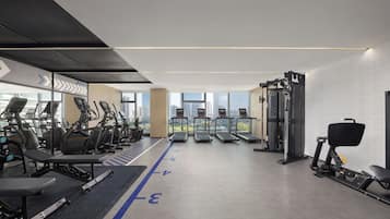 Un gimnasio moderno con cintas de correr, elípticas y equipamiento para levantamiento de pesas.