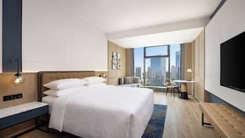 Una habitación de hotel moderna con una cama grande, un escritorio, una silla y un televisor.