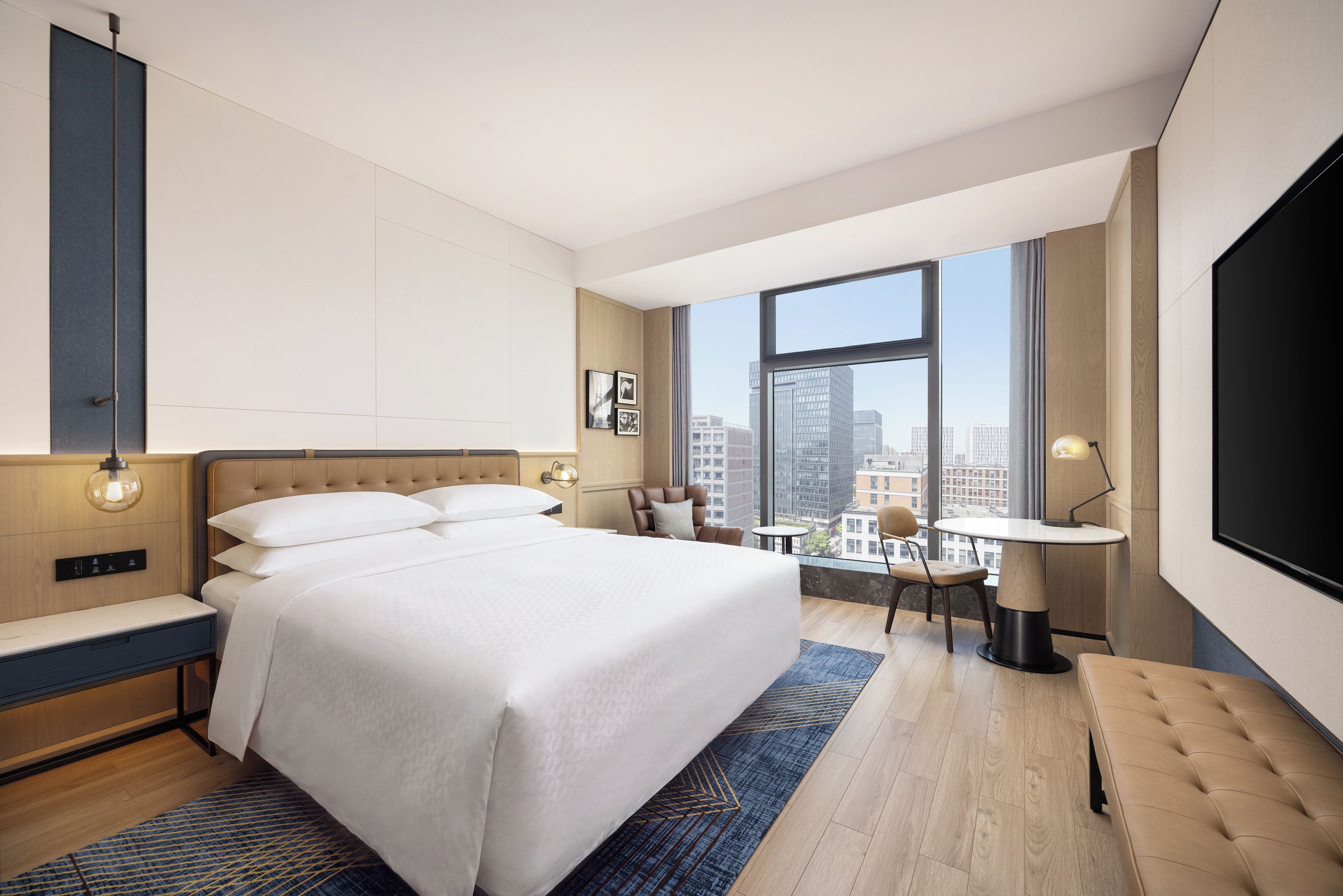 Una habitación de hotel moderna con una cama grande, un escritorio y vistas a la ciudad.