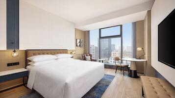 Una habitación de hotel moderna con una cama grande, un escritorio y vistas a la ciudad.