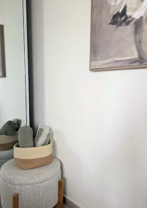 Ett rum med en rund sittpuff, en spegel och en inramad abstrakt målning på väggen.