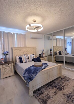 A bedroom with a bed, bedside tables, a mirror, and a ceiling fan. - Azulena - A stay between the mountains & sea! With Tesla battery & water tank (Fajardo)