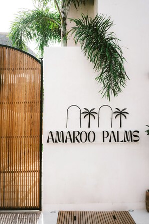 Un cartel con la leyenda 'AMAROO PALMS' e imágenes de siluetas de palmeras.