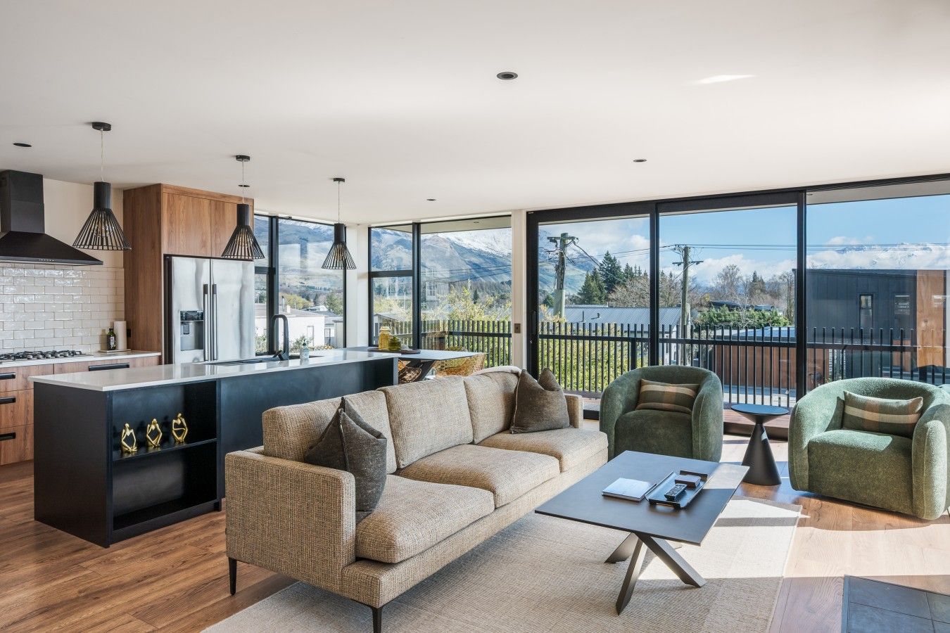 A modern kitchen with a large island, a sofa, and a view of mountains through large windows.