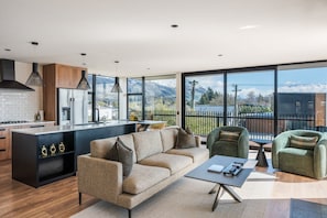 Une cuisine moderne dotée d’un grand îlot central, d’un canapé et offrant une vue sur les montagnes grâce à de grandes fenêtres.