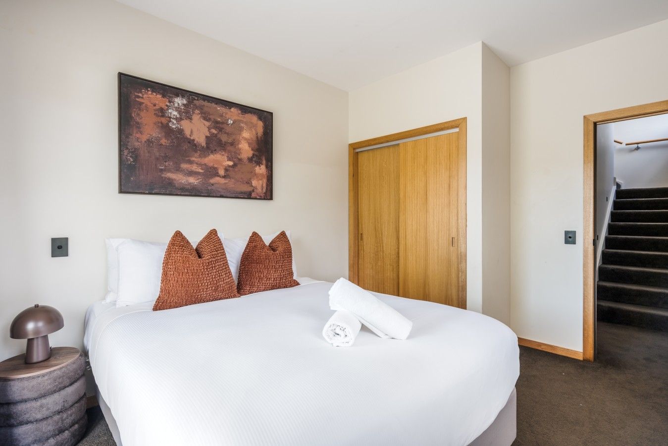 Ein Hotelzimmer mit einem großen Bett, einer Holztür und einer Treppe.