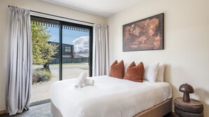Een hotelkamer met een groot bed, een schilderij aan de muur en uitzicht door de glazen deur.