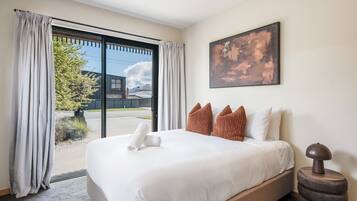 Ein Hotelzimmer mit einem großen Bett, einem Gemälde an der Wand und Blick durch die Glastür.