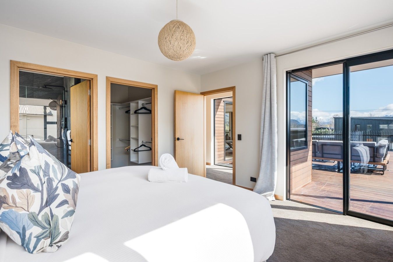 Une chambre moderne dotée d’un grand lit, d’un dressing et d’un balcon avec un espace salon extérieur.