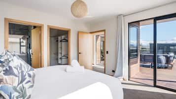 Une chambre moderne dotée d’un grand lit, d’un dressing et d’un balcon avec un espace salon extérieur.