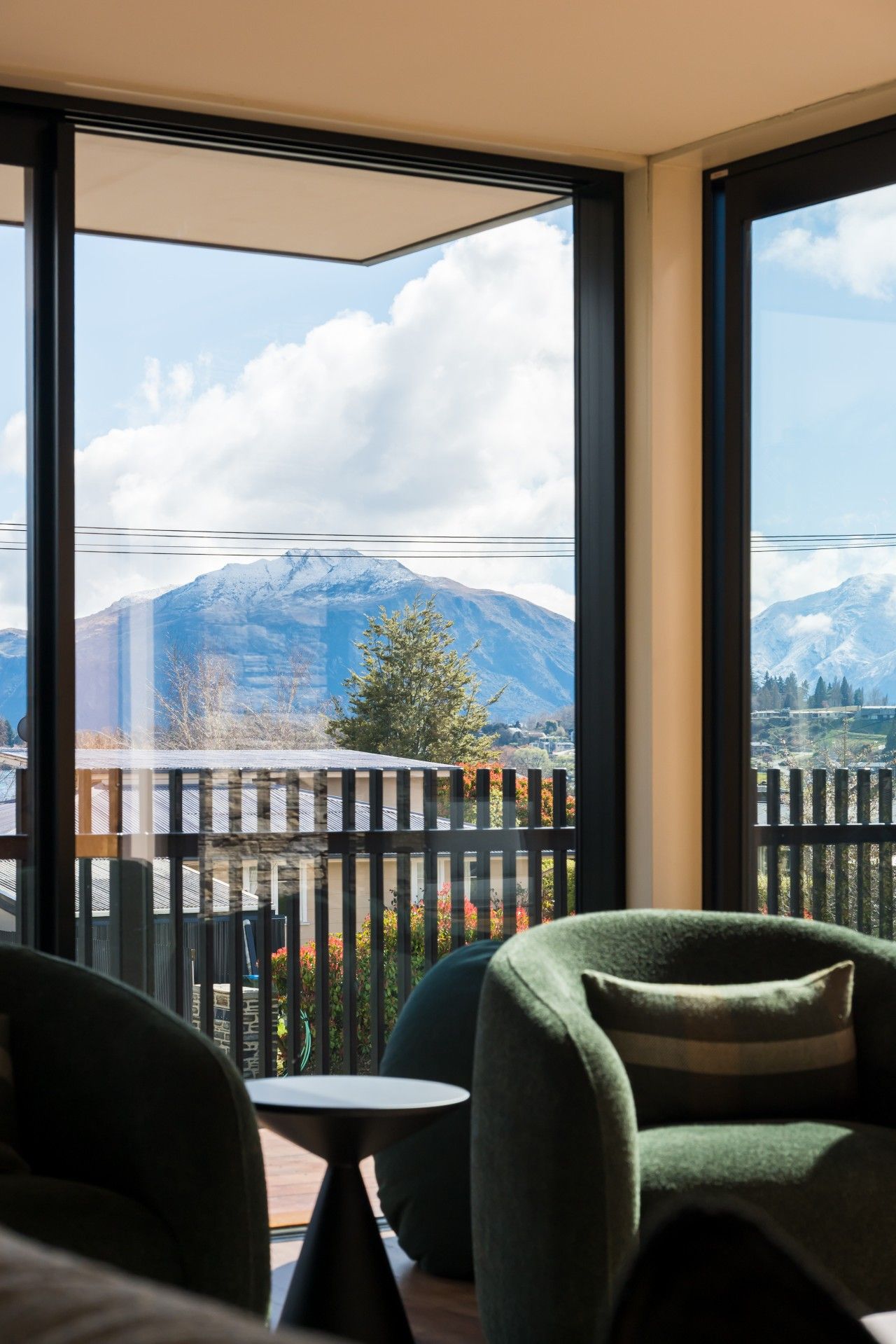 Ein Balkon mit Blick auf schneebedeckte Berge, einem Holzzaun und einem Tisch mit Stühlen.