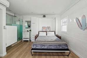 A bedroom with a bed, a dresser, a mirror, and a window. - Ocean Front Boardwalk Nest with Direct Beach Access (Santa Monica)