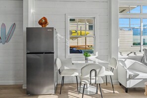 A modern kitchen with a stainless steel refrigerator, white chairs, and a window with a view of boats. - Ocean Front Boardwalk Nest with Direct Beach Access (Santa Monica)