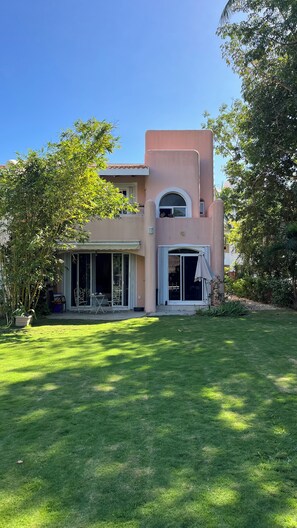 A two-story house with a flat roof, large windows, and a covered patio area.