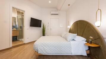 Una camera da letto con un letto, un comodino, una TV a parete e un'anta che dà sul bagno.