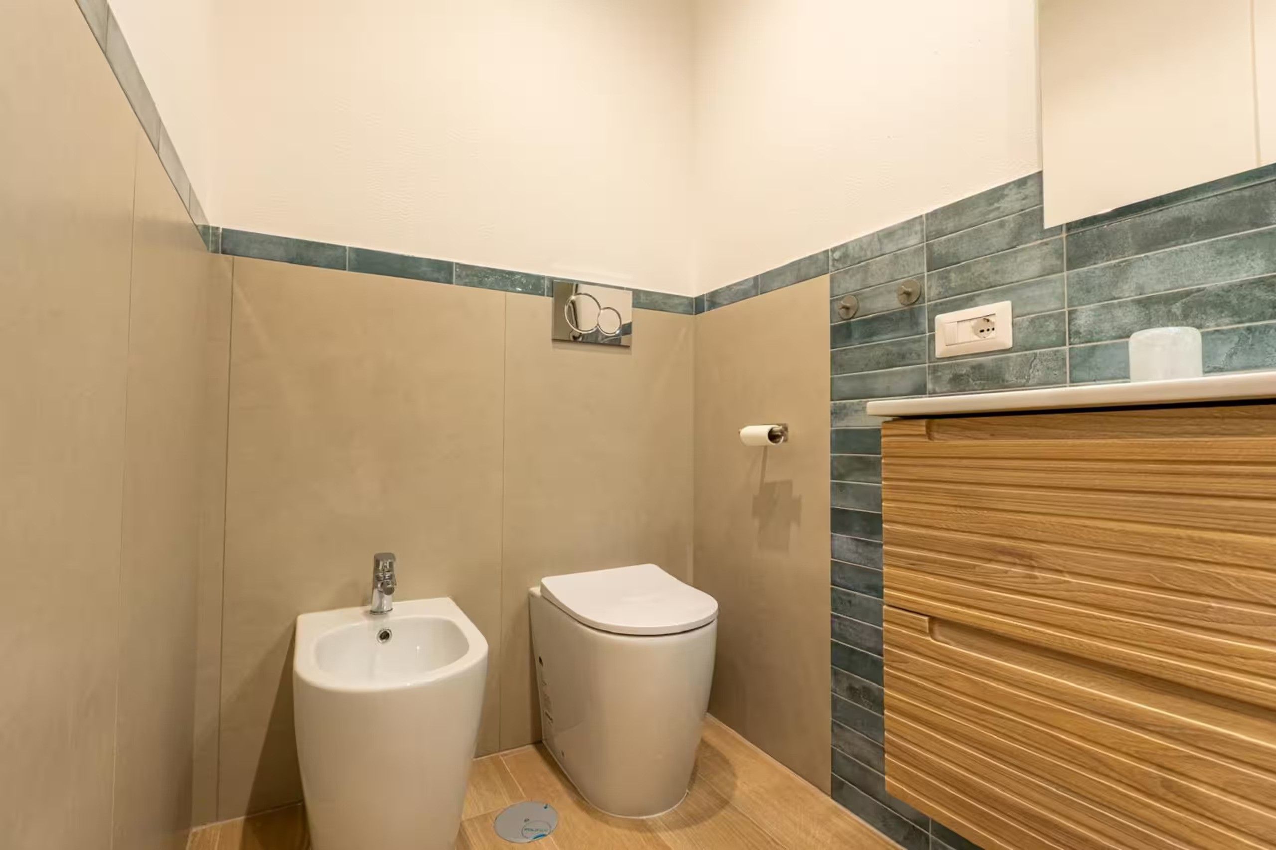 A bathroom with a bidet, toilet, and wooden vanity.