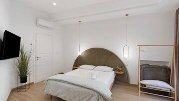 Een slaapkamer met een bed, nachtkastje, hanglamp en een aan de muur bevestigde televisie.