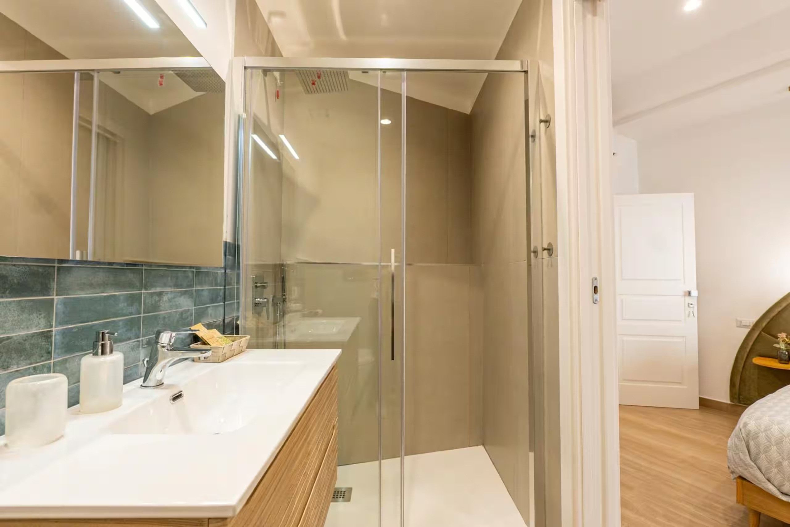 Un bagno moderno con cabina doccia in vetro, mobile lavabo in legno e un ampio specchio.