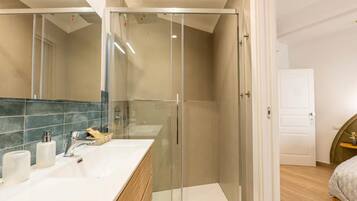 Un bagno moderno con cabina doccia in vetro, mobile lavabo in legno e un ampio specchio.