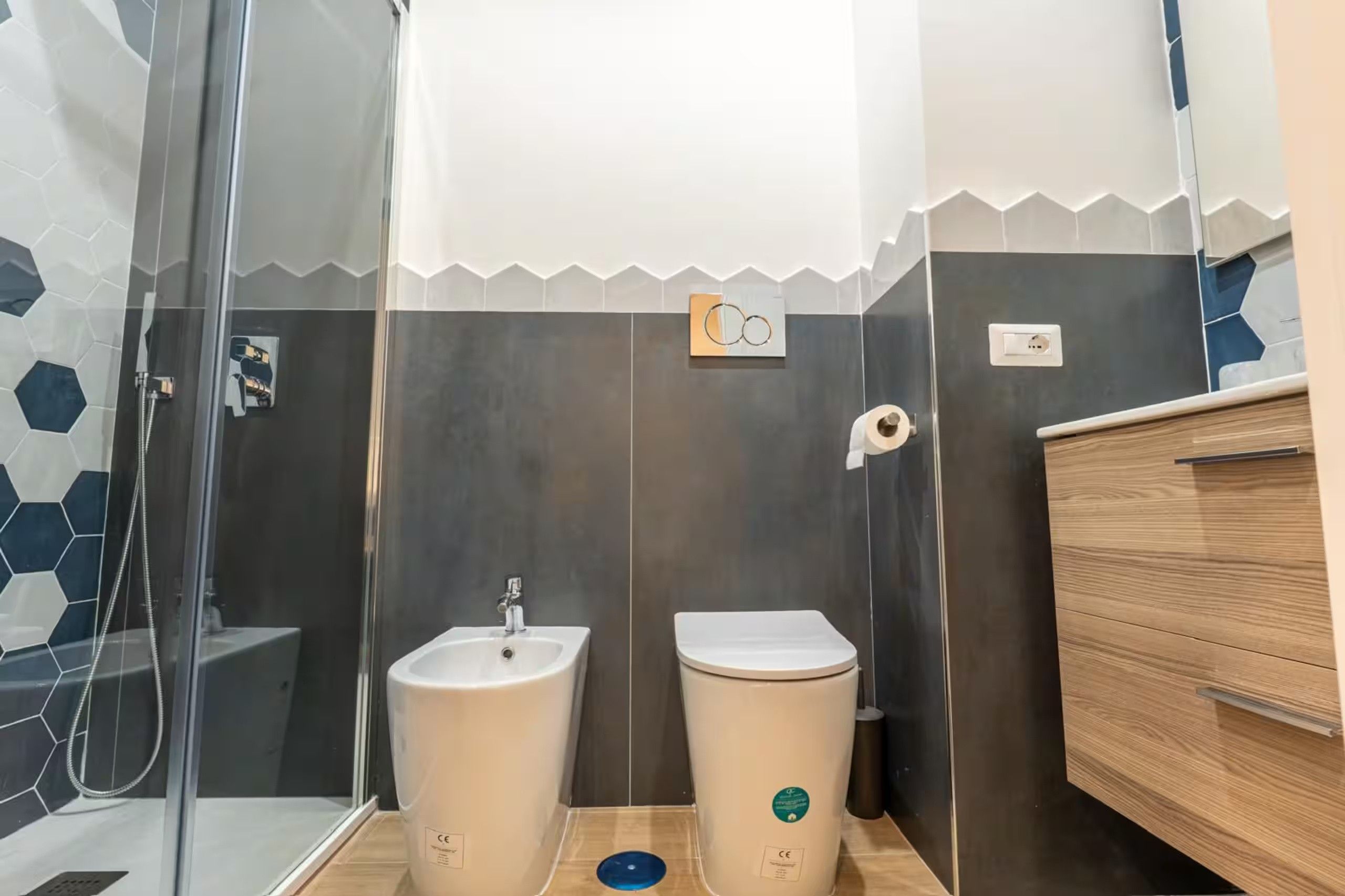 Un bagno con doccia, lavandino, WC e un armadietto in legno.
