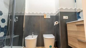 Un bagno con doccia, lavandino, WC e un armadietto in legno.