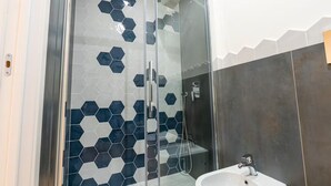 Ein modernes Badezimmer mit einer gläsernen Duschkabine, sechseckischen Fliesen und einem weißen Waschbecken.