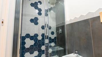Ein modernes Badezimmer mit einer gläsernen Duschkabine, sechseckischen Fliesen und einem weißen Waschbecken.