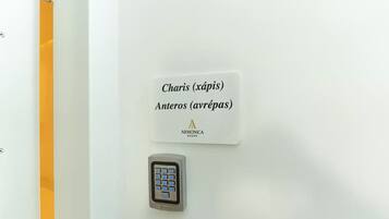Una camera d'albergo con serratura a combinazione e un cartello che indica i numeri delle stanze 'Charis (xápis)' e 'Anteros (avrépas)'.