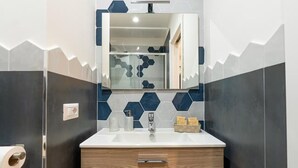 Ein Badezimmer mit einem weißen Waschbecken, einem Spiegel darüber und einem Holzkabinet darunter.