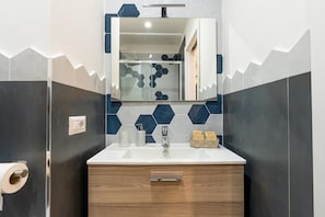 Een badkamer met een wit wastafel, een spiegel erboven en een houten kastje eronder.