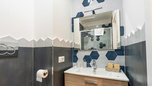 Ein Badezimmer mit Spiegel, Toilettenpapierhalter, Waschbecken und einem Waschtisch mit Spiegel.