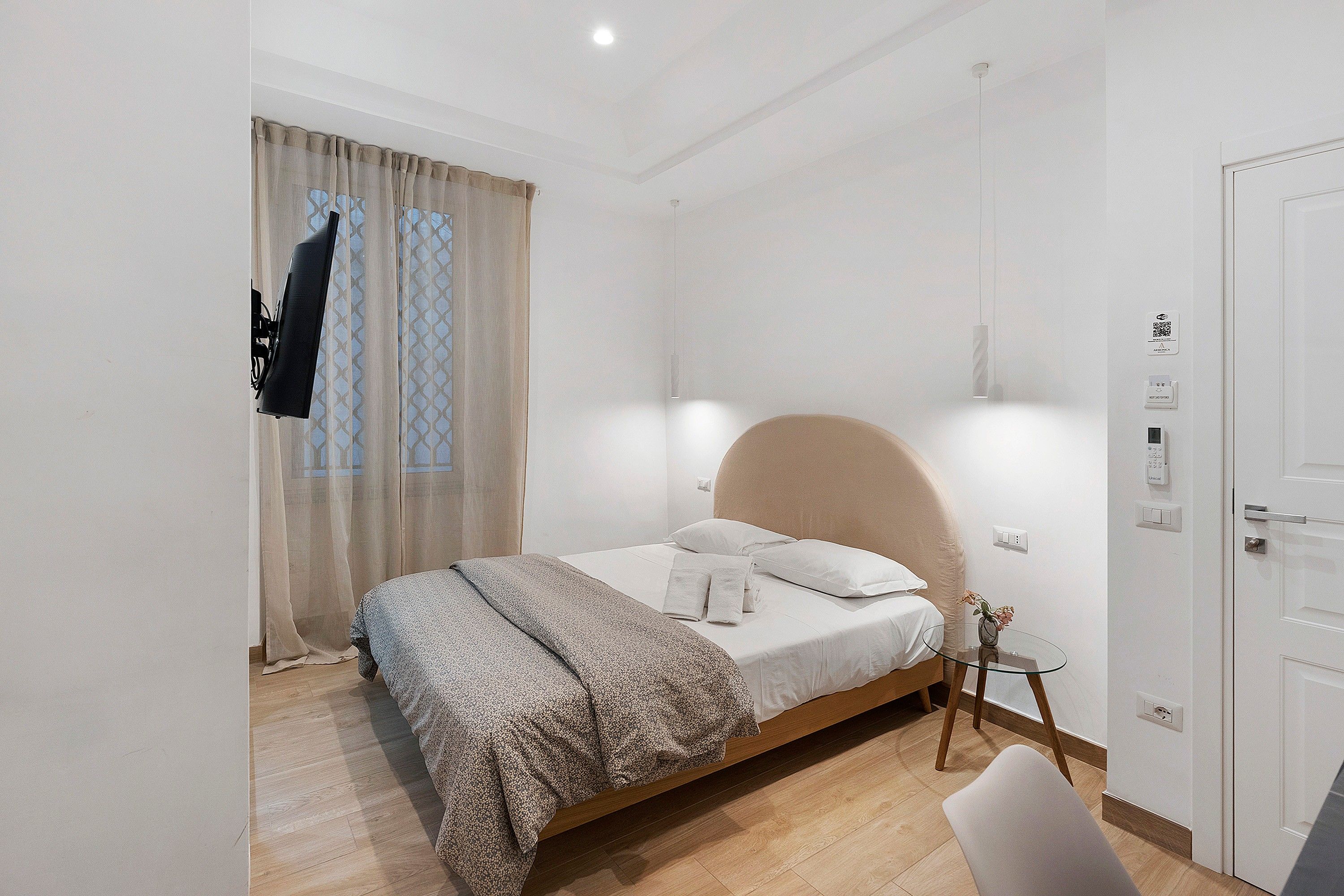 Een slaapkamer met een bed, een nachtkastje, een stoel, een deur en een raam met gordijnen.