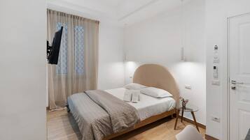 Een slaapkamer met een bed, een nachtkastje, een stoel, een deur en een raam met gordijnen.