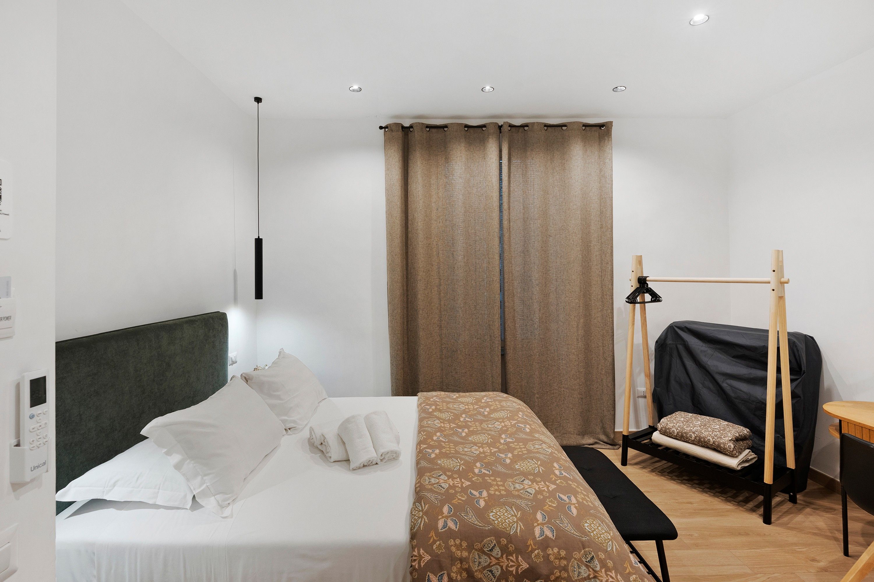 Una camera d'albergo con un letto, un comodino, una lampada e una finestra con tende.