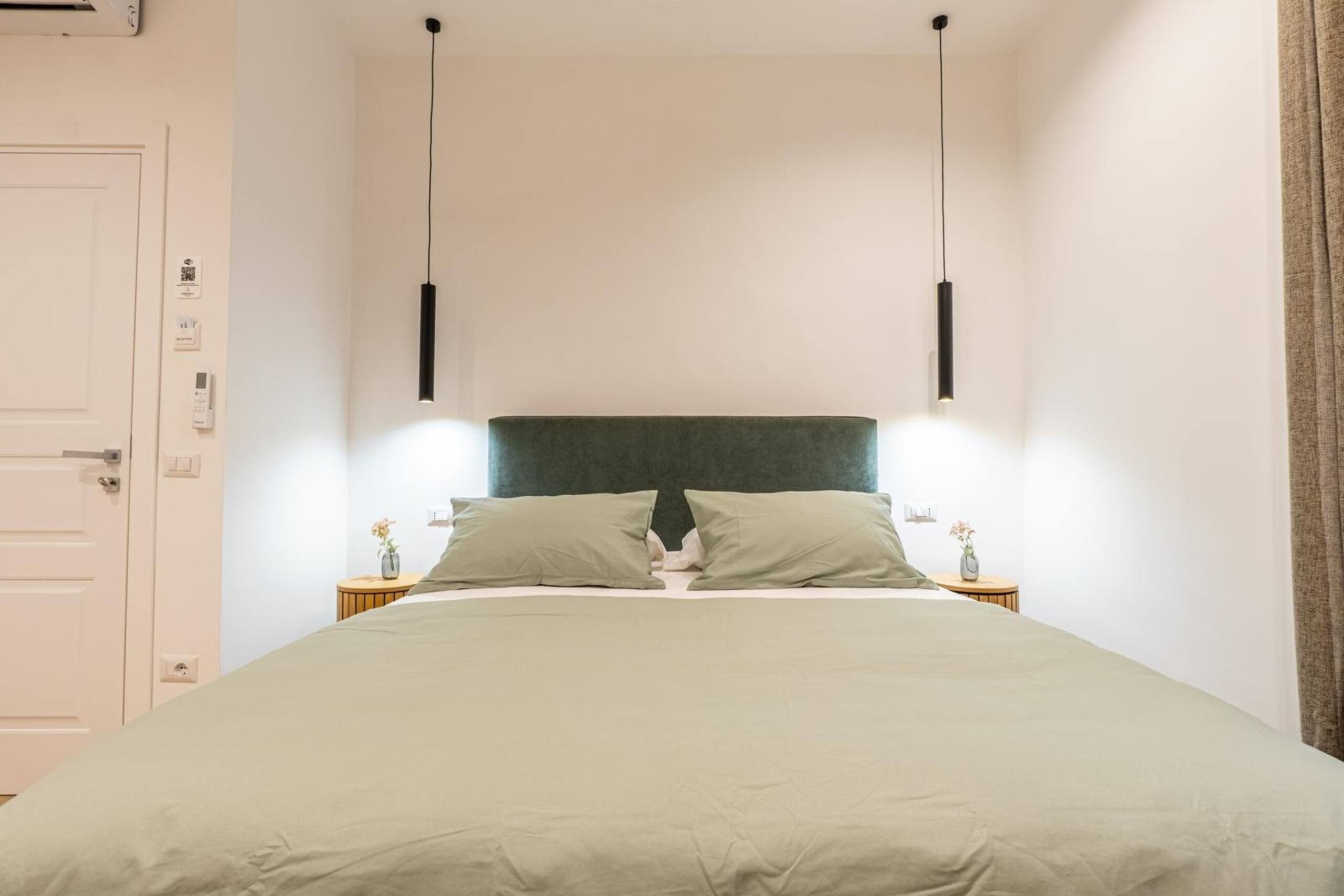 Ein schlichter Schlafzimmerbereich mit Bett, Nachttischen und einer Tür.