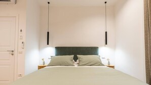 Ein schlichter Schlafzimmerbereich mit Bett, Nachttischen und einer Tür.