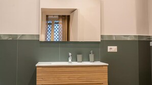 Ein Badezimmer mit einem Holzkonsolenunterschrank, einem Spiegel und einem Waschbecken.