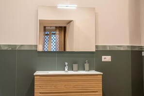 Een badkamer met een houten wastafelmeubel, een spiegel en een wastafel.