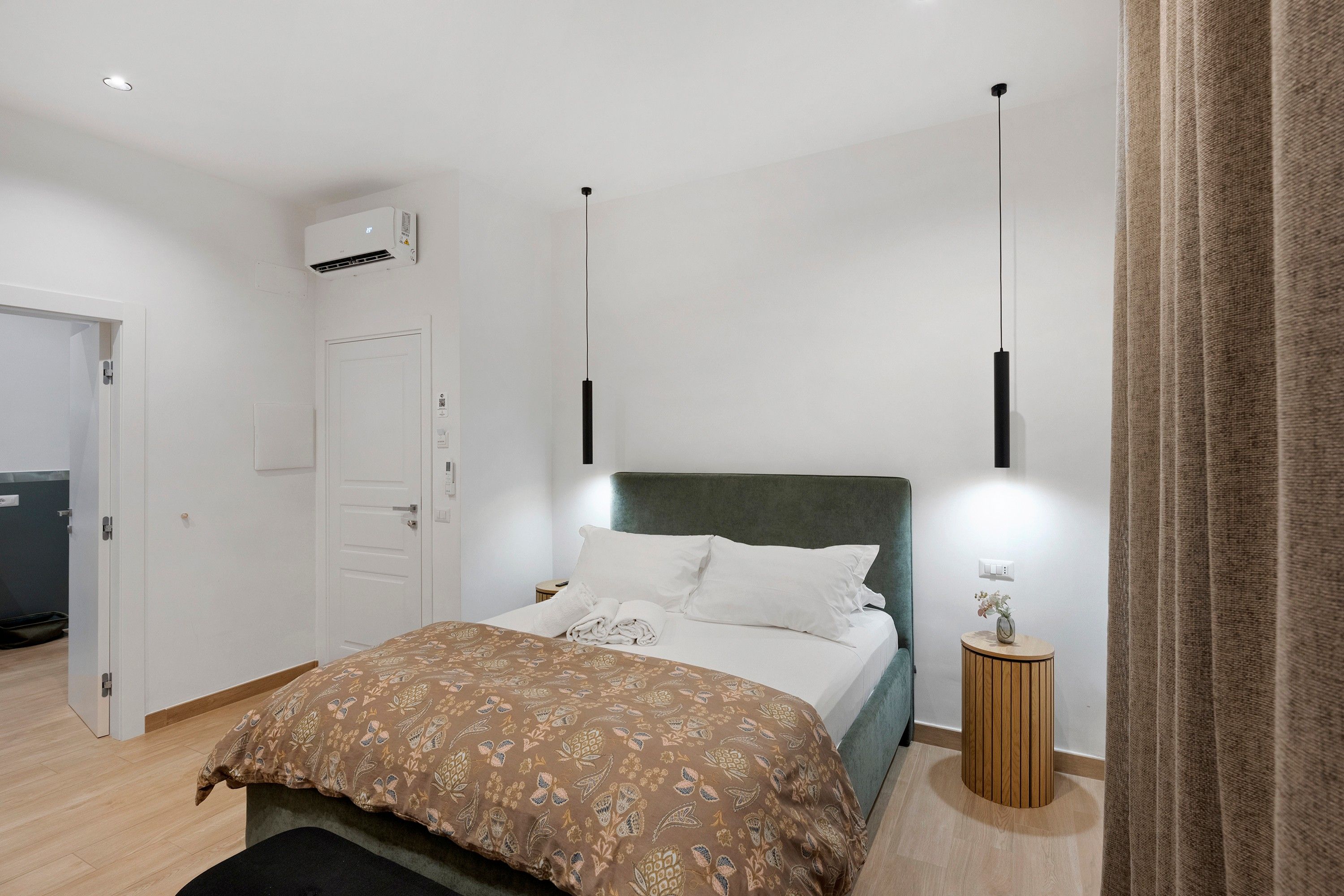 Una camera d'albergo con un letto, un comodino e un condizionatore d'aria.