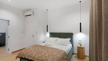 Una camera d'albergo con un letto, un comodino e un condizionatore d'aria.