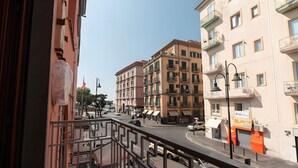 Une vue de rue avec des immeubles, un piéton et des voitures garées.