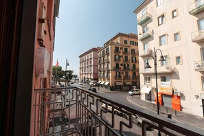 Katunäkymä, jossa näkyy rakennuksia, jalankulkija ja parkkeerattuja autoja.